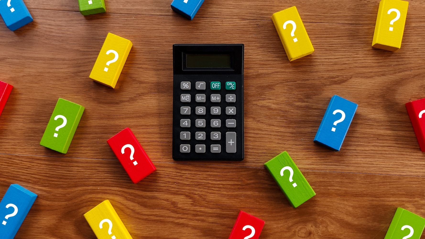 A calculator surrounded by question blocks on a brown wood background