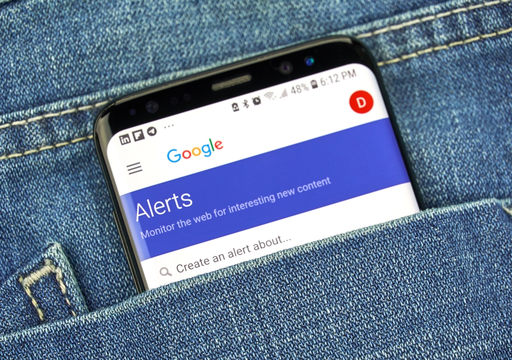 A phone in a back pocket that shows google alerts