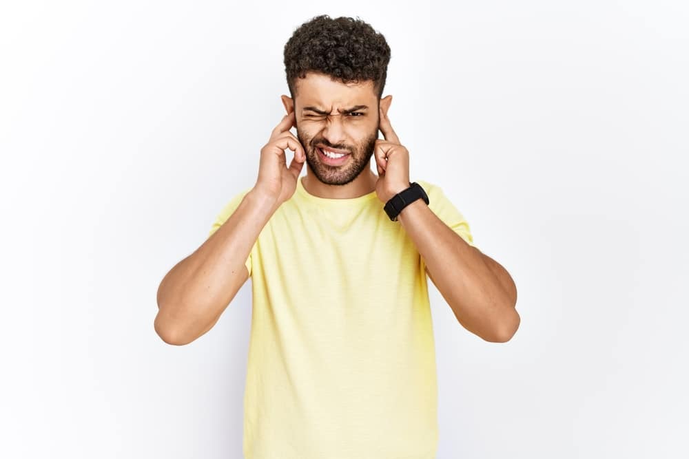 Man with hands over his ears to block noise