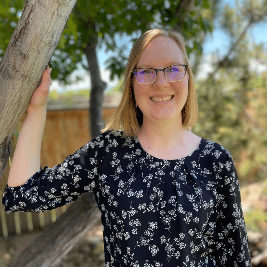 Tessa smiling next to a tree