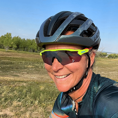 meredith smiling wearing yellow rimmed sunglasses and a black bicycle helmet