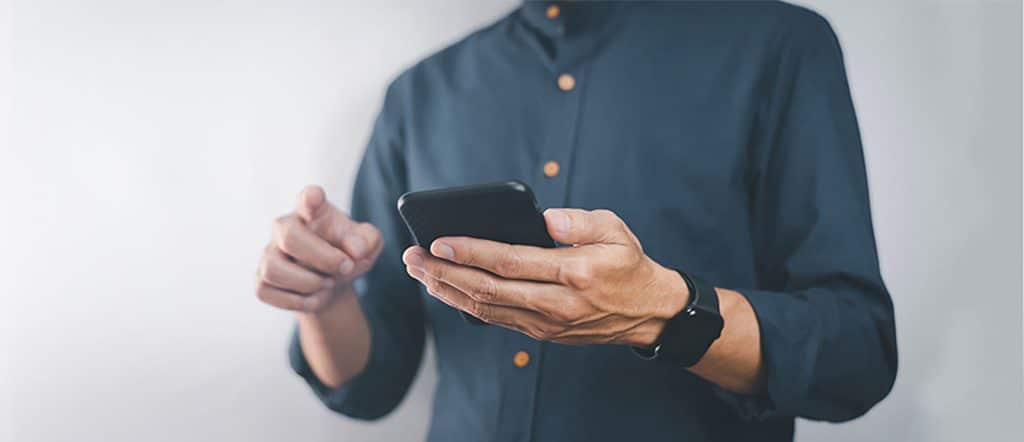 person in a blue shirt typing on a cell phone