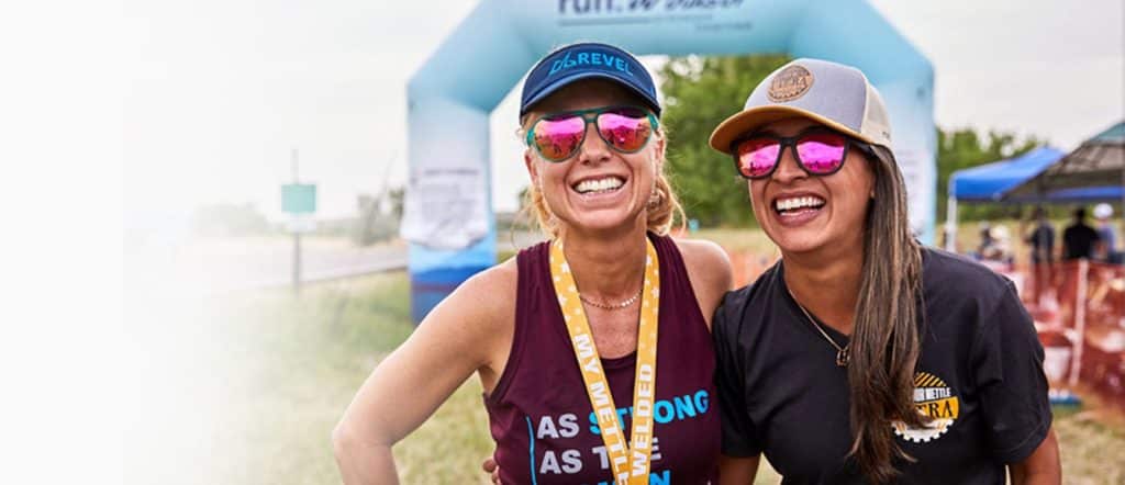 two women smiling at a race event