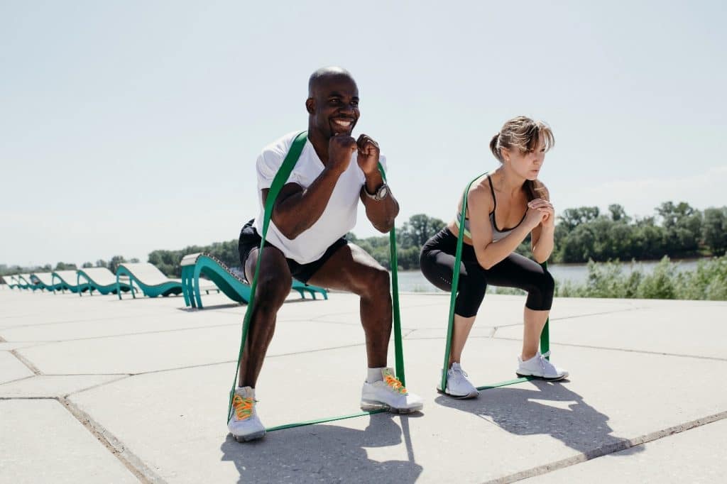 A man and woman doing resistance band squats