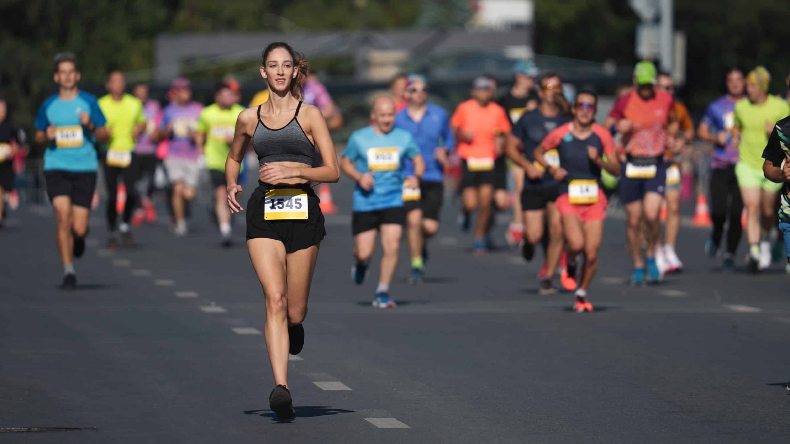Runners wearing race bibs and running on a road during a race