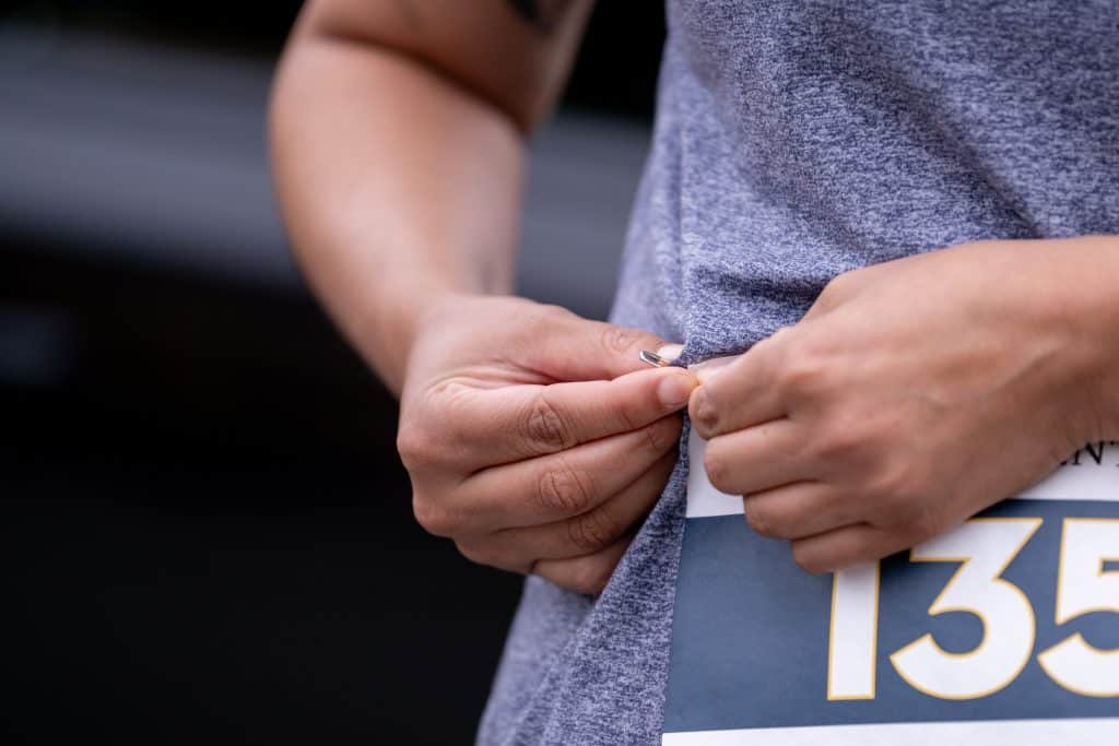 A person pinning a race bib to their t-shirt