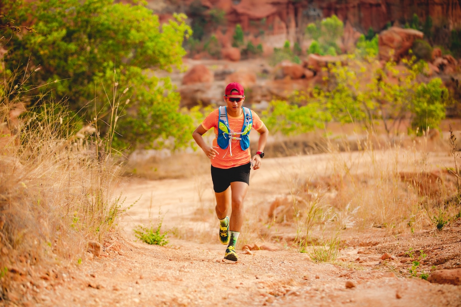 A male running on a desert trail wearing a hydration vest