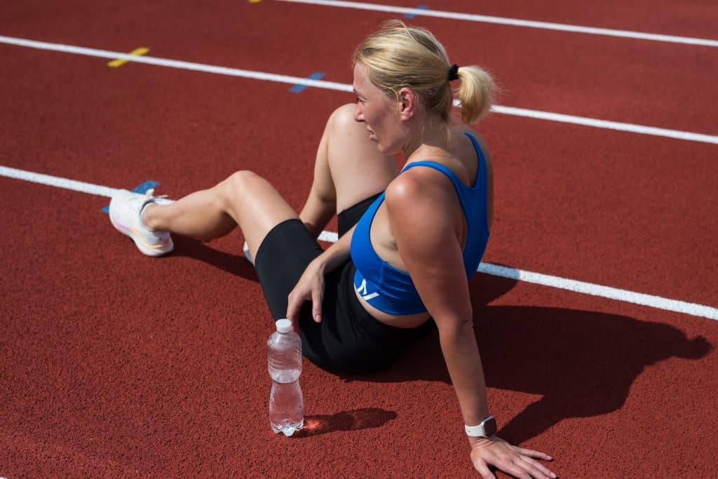 A woman sitting on a track next to a water bottle