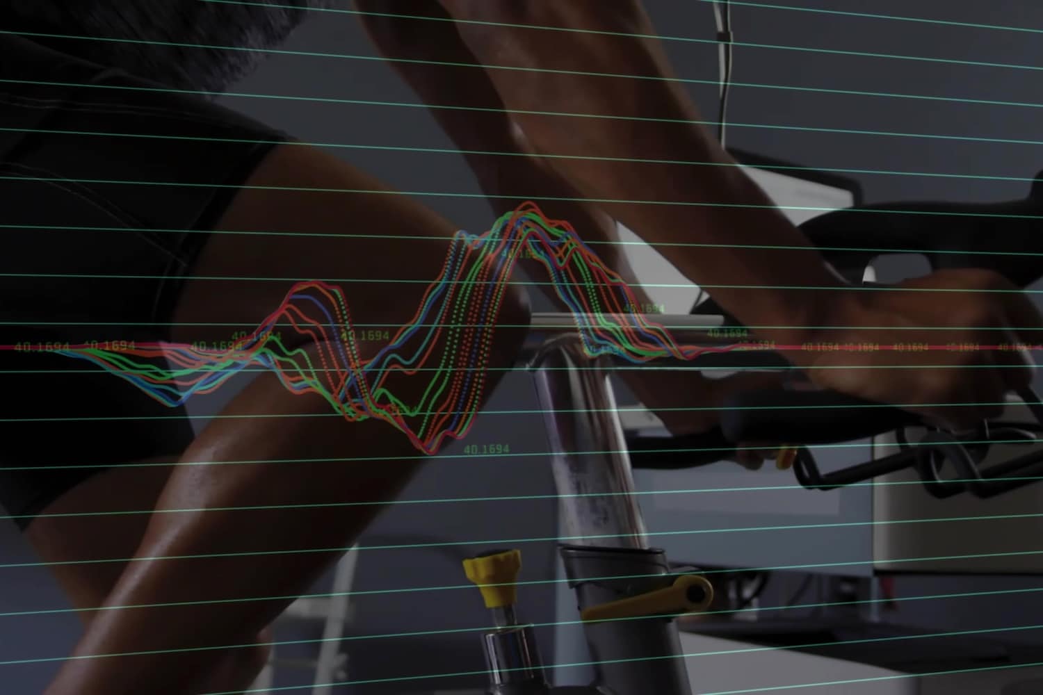 Pedaling man wearing fitted athletic gear on stationary bike in fitness lab, with waveform overlay