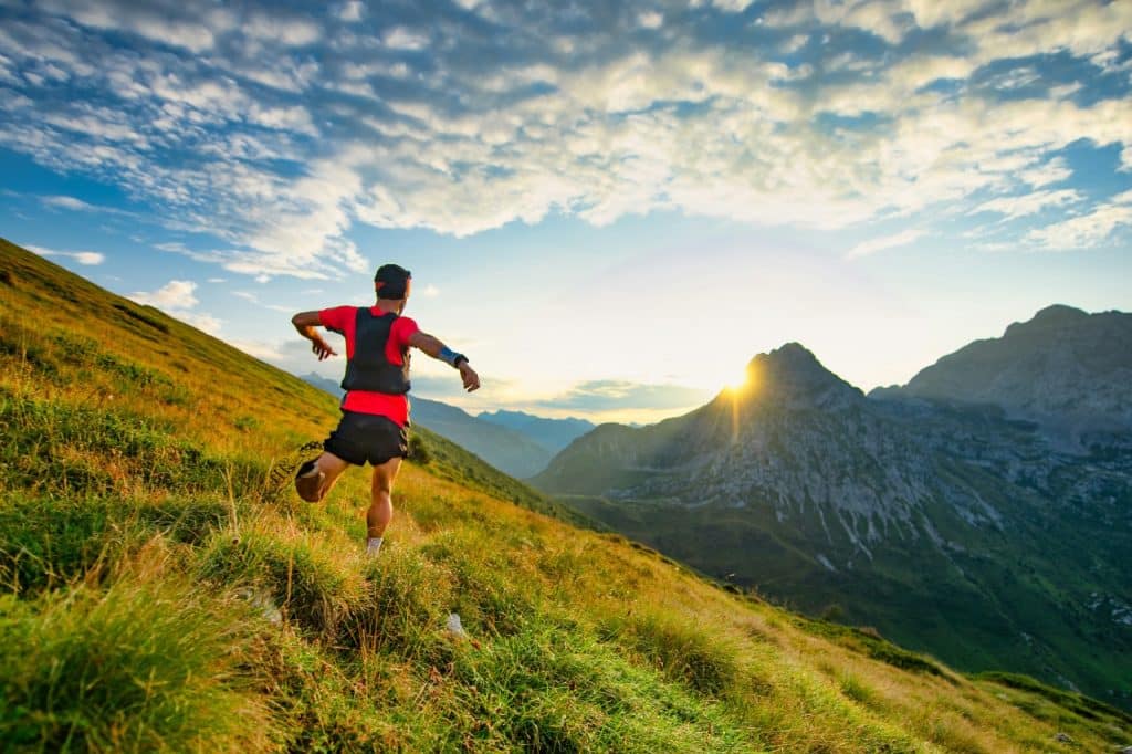 Trail runner descending a grassy mountain trail